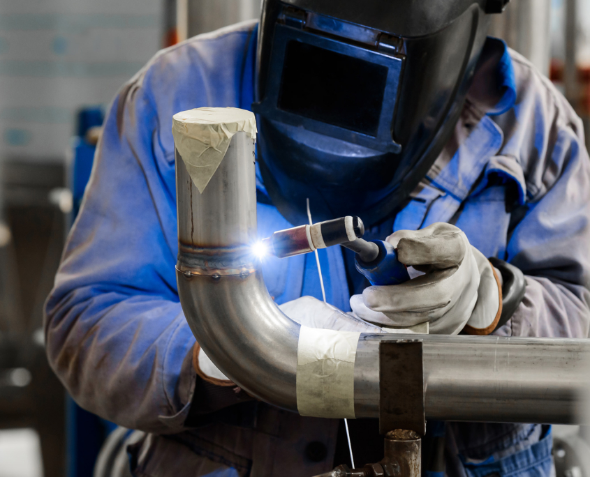 Male In Face Mask Welds With Argon Arc Welding Pipes
