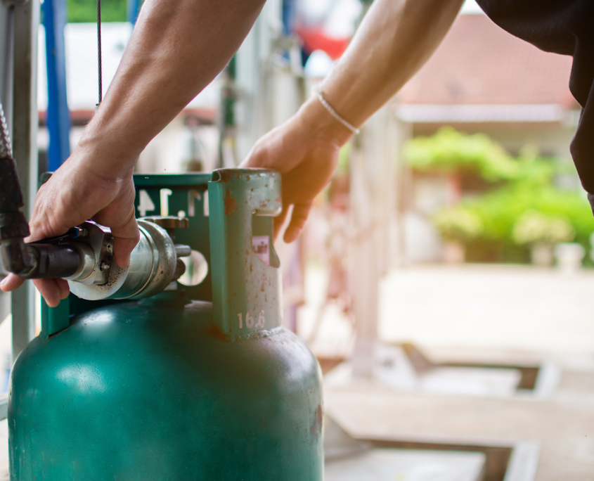 A Male Worker Uses A Gas Cylinder Device For A Customer